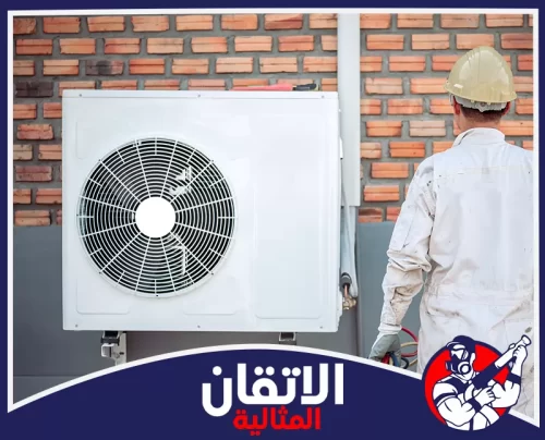 تنظيف مجرى صرف المكيفات في الخبر 0567008659 شركة أتقان المثالية فني مختص يرتدي خوذة الأمان أثناء فحص وحدة التكييف الخارجية لضمان كفاءة التبريد وجودة التركيب