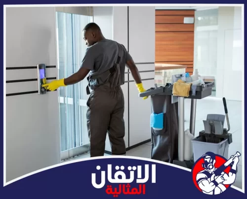 تنظيف سلالم العمائر بالظهران 0567008659 شركة أتقان المثالية عامل نظافة محترف يستعد للعمل أمام المصعد مع أدواته.