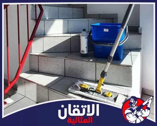 تنظيف المصاعد من الداخل والخارج بالقطيف 0567008659 الأتقان المثالية أدوات تنظيف على درج مدخل عمارة في القطيف تشمل ممسحة ودلو ومواد تنظيف جاهزة لغسل الأرضيات والسيراميك بكفاءة.