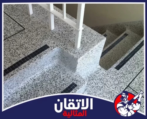 تنظيف رخام المداخل بالاحساء 0567008659 شركة أتقان المثالية درج وممر داخلي بأرضية موزايكو أو إيبوكسي منقطة بالأبيض والأسود، مجهزة بشرائط سوداء مانعة للانزلاق.