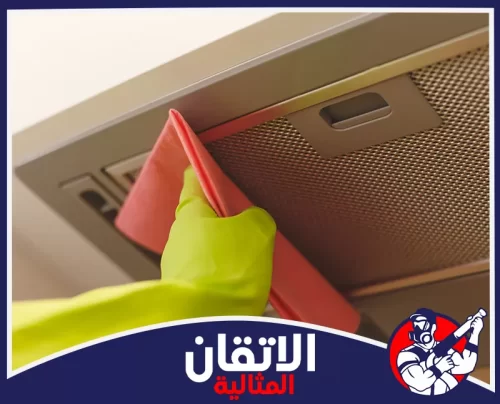 تنظيف مداخن المطاعم والفلاتر بالأحساء 0567008659 شركة أتقان المثالية يد بقفاز أصفر تمسح بقماش وردي إطار فلتر شفاط المطبخ الفضي الشبكي من أجل تنظيف دقيق وإزالة الدهون والترسبات.