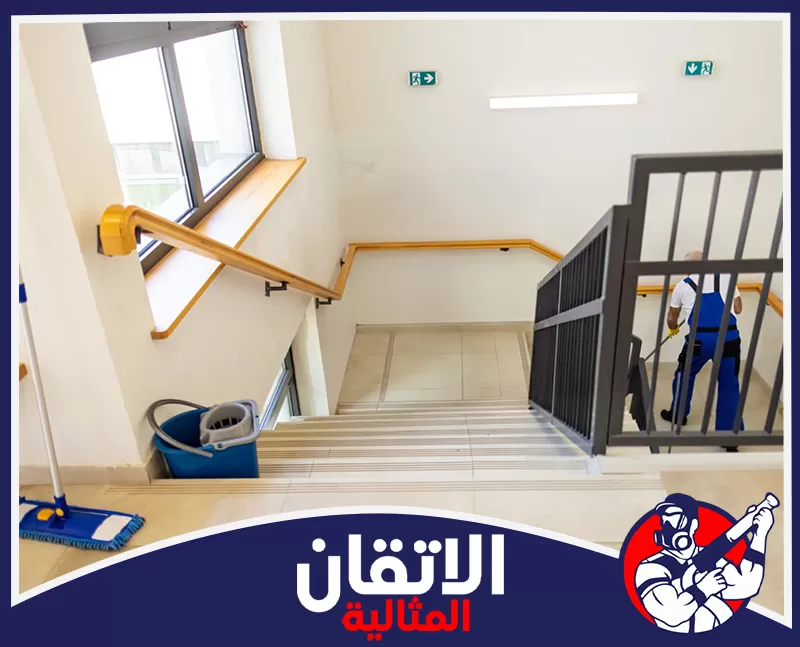 تنظيف الممرات والسلالم في الخبر 0567008659 شركة أتقان المثالية عامل نظافة يقوم بمسح الدرج، و دلو ماء أزرق على الدرجة السفلية.