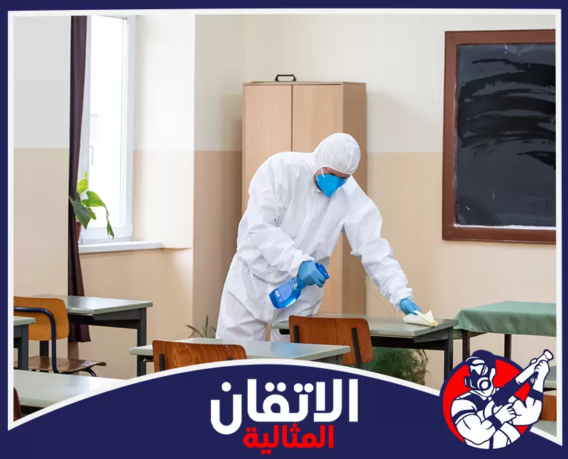 تنظيف الواجهات والنوافذ والأبواب في القطيف 0567008659 شركة أتقان المثالية شخص ببدلة وقائية كاملة وقناع أزرق ينظف مقعداً باستخدام بخاخ ومنديل