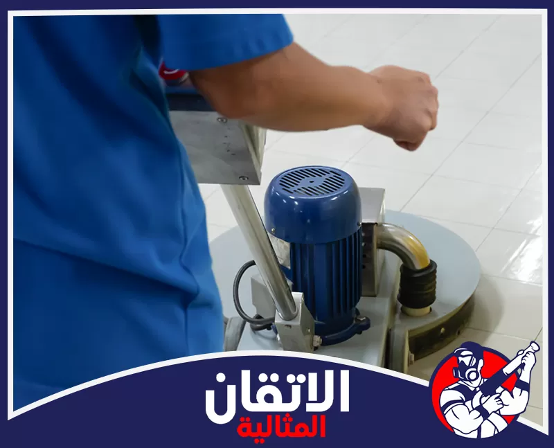 جلي البلاط الموزايكو في الأحساء 0567008659 شركة أتقان المثالية عامل في يشغل ماكينة تنظيف ذات محرك أزرق على أرضية بلاط بيضاء.